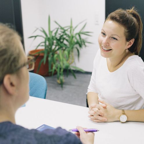 Eine Studentin und eine Studienberaterin sitzen sich an einem Tisch gegen&uuml;ber.