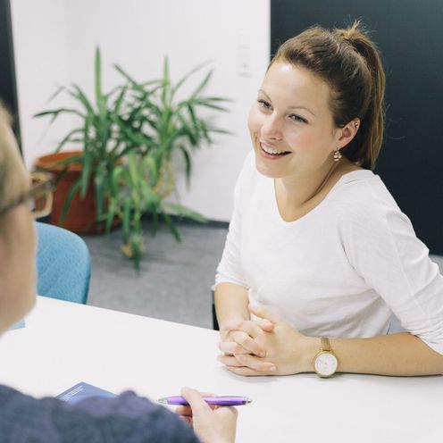 Eine Studentin und eine Studienberaterin sitzen sich an einem Tisch gegen&uuml;ber.
