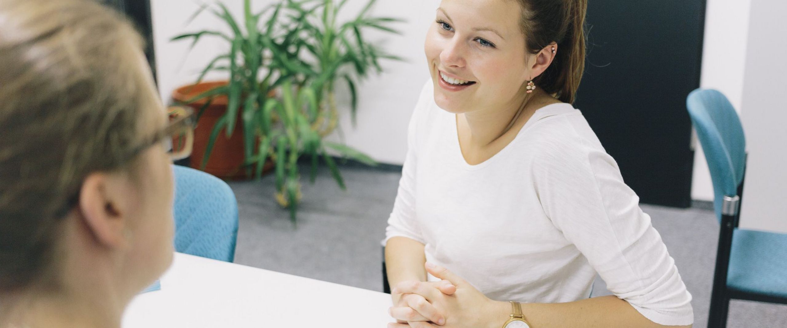 Eine Studentin und eine Studienberaterin sitzen sich an einem Tisch gegenüber.