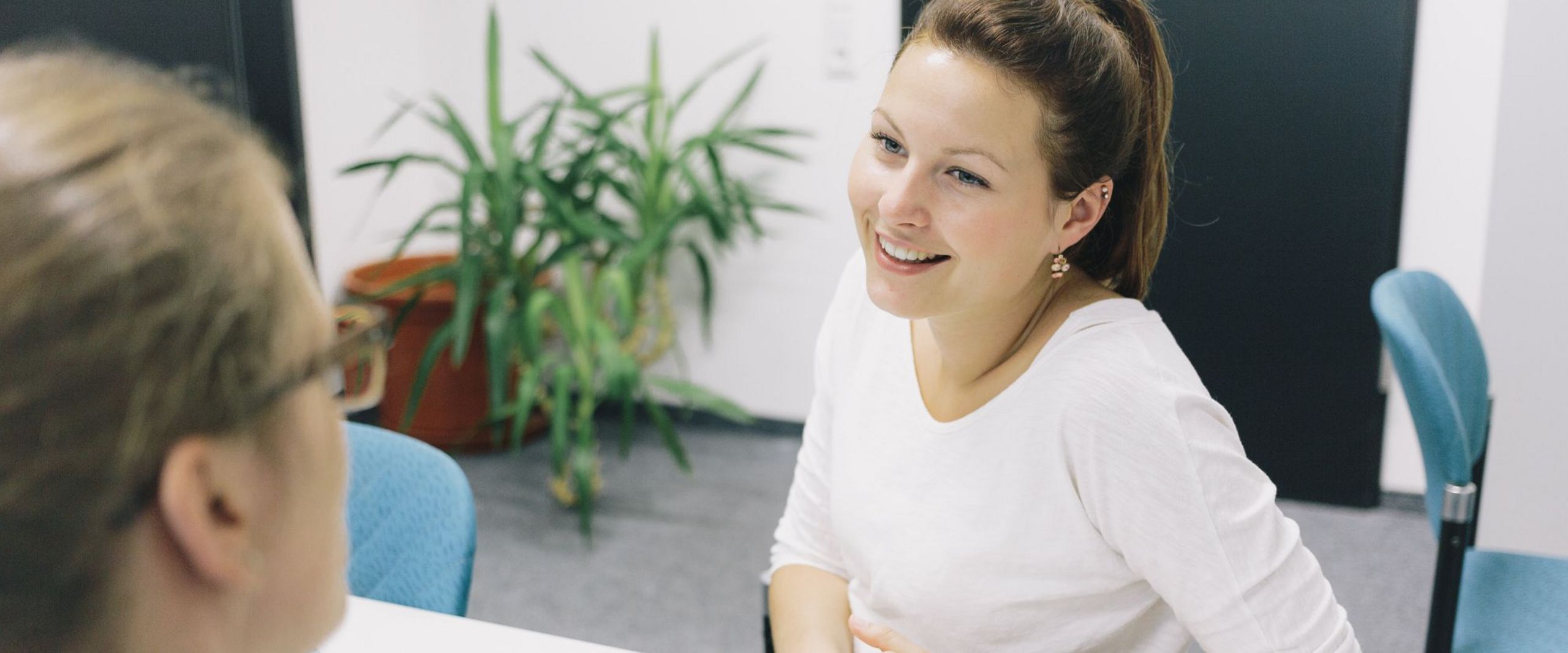 Eine Studentin und eine Studienberaterin sitzen sich an einem Tisch gegenüber.