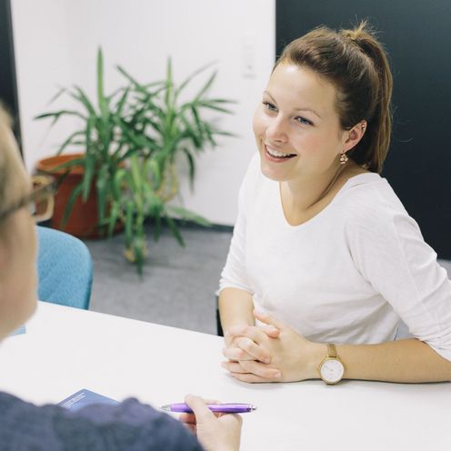 Eine Studentin und eine Studienberaterin sitzen sich an einem Tisch gegen&uuml;ber.
