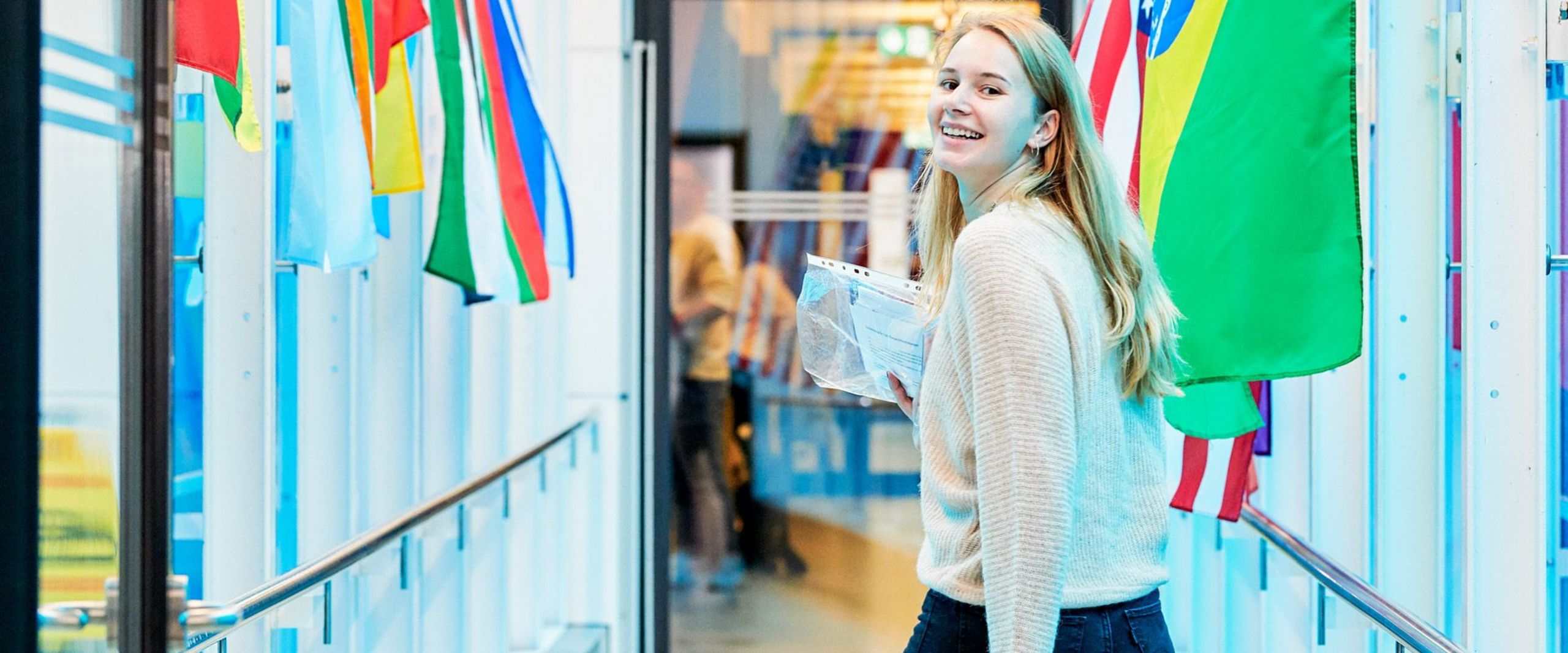 Eine Studentin läuft an verschiedenen Länderflaggen vorbei