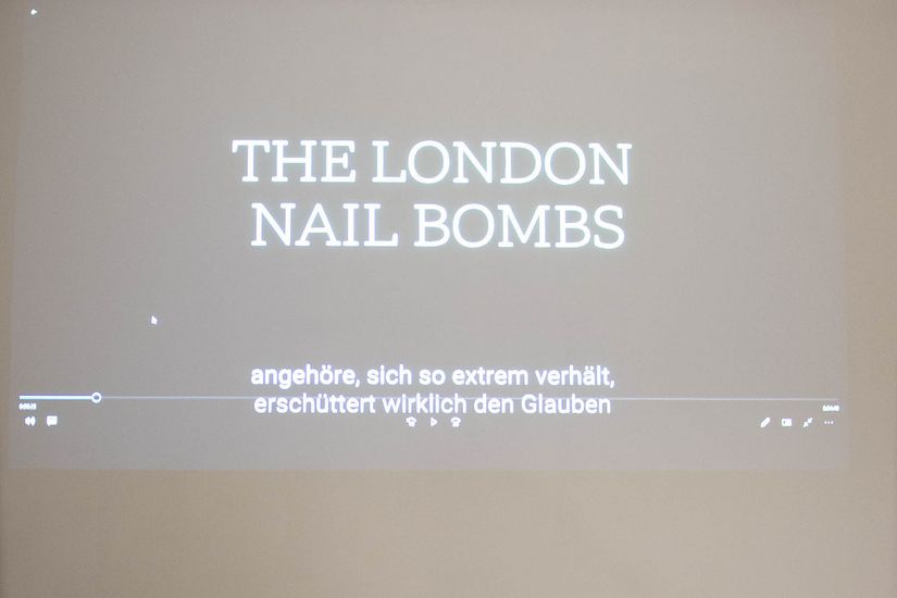 Ein Beamerbild an einer Wand. Es l&auml;uft gerade ein Video mit dem Thema "The London Nail Bombs".