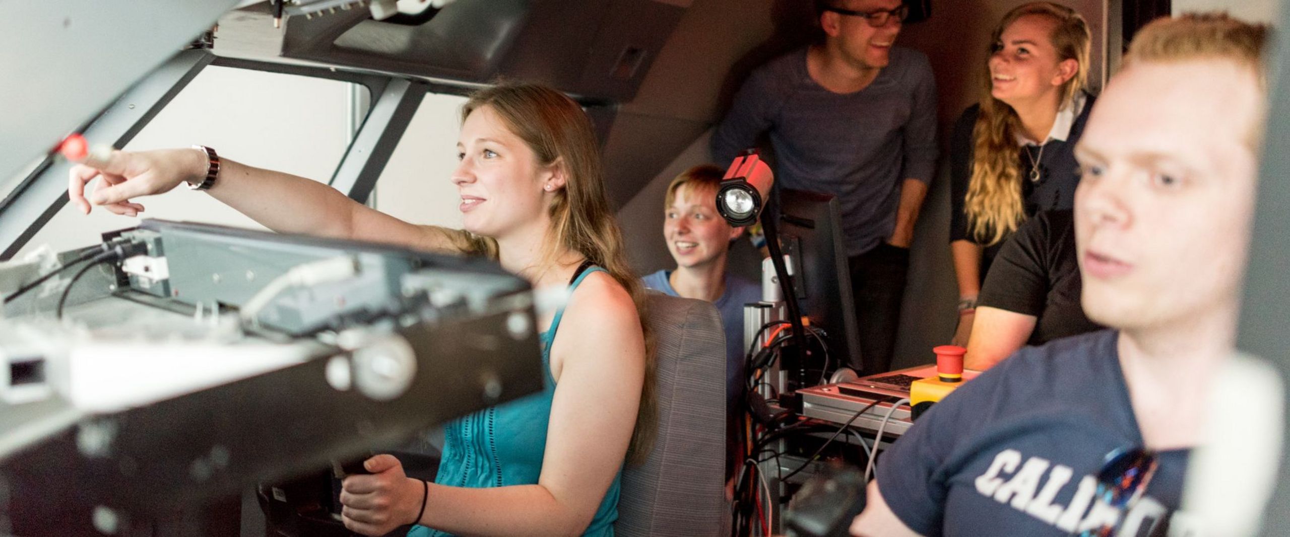 Eine Gruppe Studierender sitzt im Cockpit eines Flugsimulators.