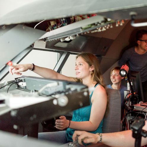 Eine Gruppe Studierender sitzt im Cockpit eines Flugsimulators.