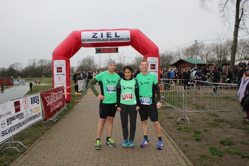 Ein Gruppenbild von drei Läufern und dahinter die Ziellinie.