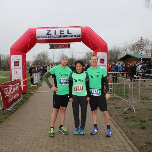 Ein Gruppenbild von drei L&auml;ufern und dahinter die Ziellinie.