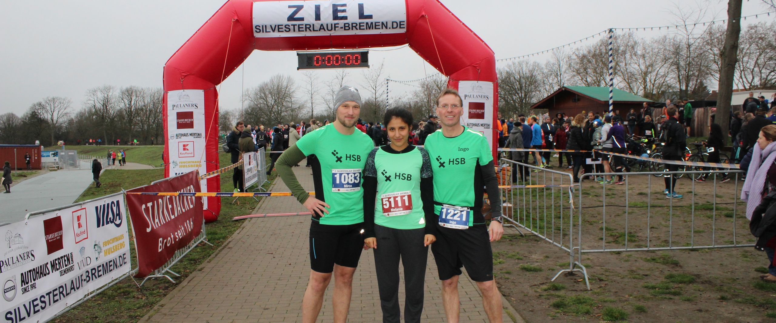 Ein Gruppenbild von drei L&auml;ufern und dahinter die Ziellinie.