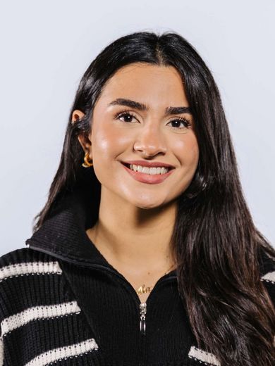 Auf dem Bild ist Cargla Demir zusehen. Sie hat langes schwarzes Haar und trägt ein schwarz-weiß gestreiftes Strickkleid. 