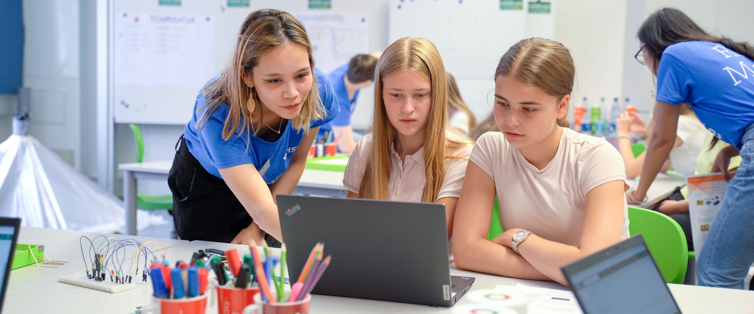 meetMINT Sommerferienprogramm 2024 Das studentische Role Model Sophie Mießner unterstütz die Schülerinnen Sylvia Wirth und Luise Büsing beim Programmieren.