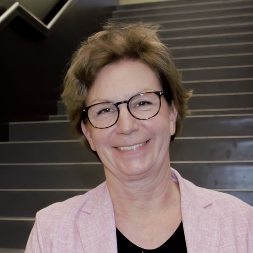 Frau mit Blumenstrau&szlig; steht auf Treppe und lacht in die Kamera