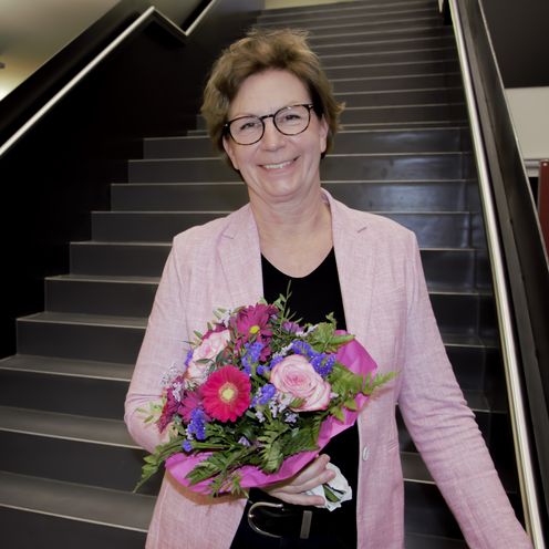 Frau mit Blumenstrau&szlig; steht auf Treppe und lacht in die Kamera