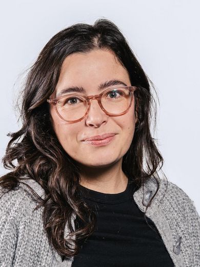 Auf dem Foto ist Annika Müller zusehen. Sie hat langes schwarzes Haar. Sie trägt eine Brille und eine graue Strickjacke über einem schwarzen Shirt.