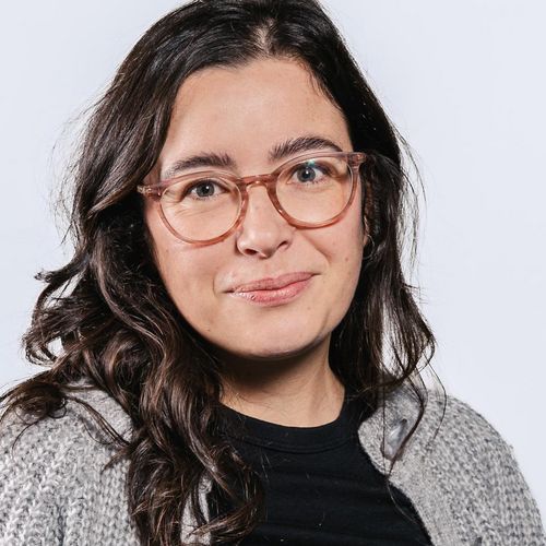 Auf dem Foto ist Annika M&uuml;ller zusehen. Sie hat langes schwarzes Haar. Sie tr&auml;gt eine Brille und eine graue Strickjacke &uuml;ber einem schwarzen Shirt.