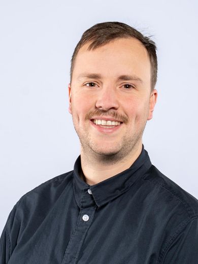 Auf dem Bild ist Henrik Scheibe zusehen. Er hat kurze blonde Haare und einen Drei-Tage-Bart. Er tr&auml;gt ein dunkelblaues Hemd. 