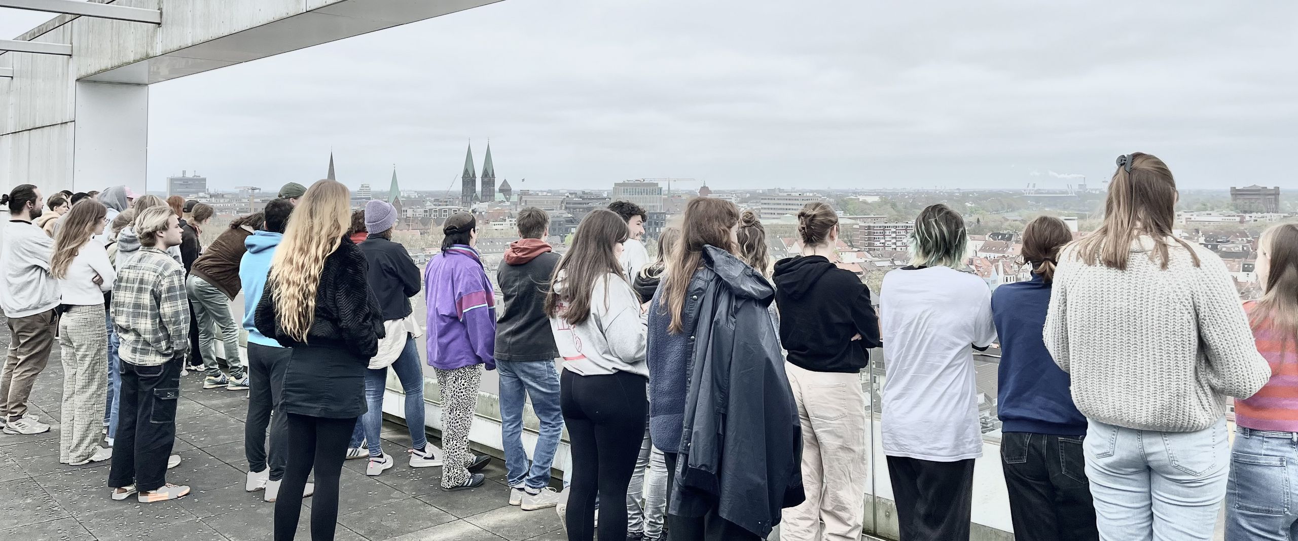 gruppe von Menschen steht auf einer Dachterrasse und schaut in die Ferne