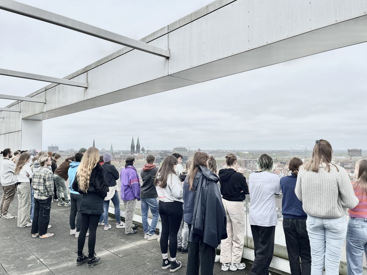 gruppe von Menschen steht auf einer Dachterrasse und schaut in die Ferne