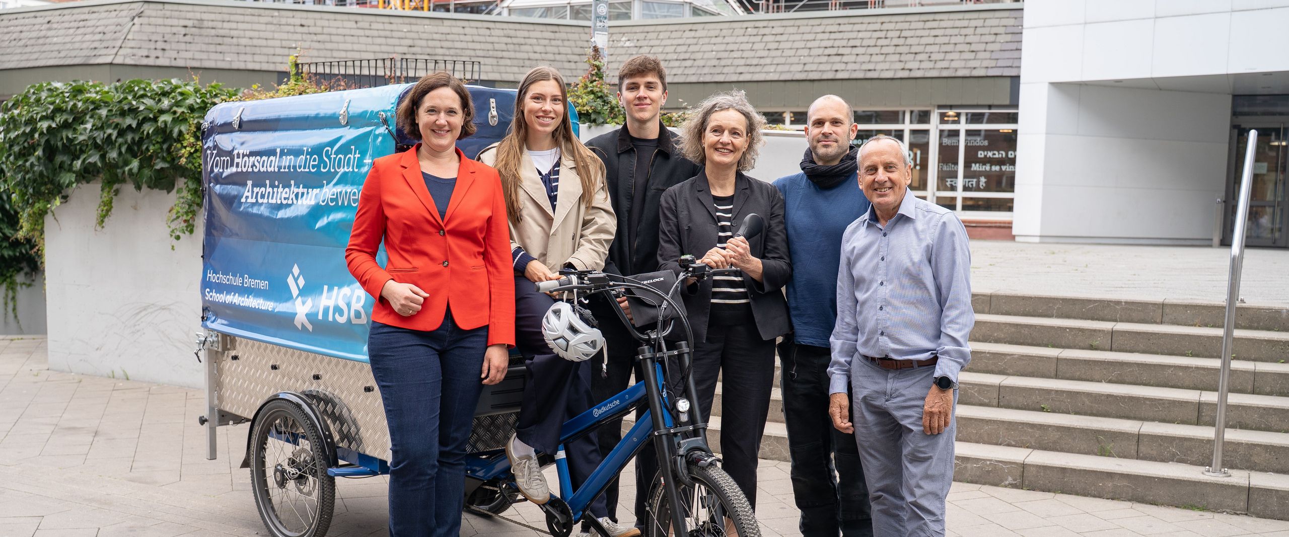 Gruppenbild mit M&auml;nnern und Frauen vor einem Lastenfahrrad. 