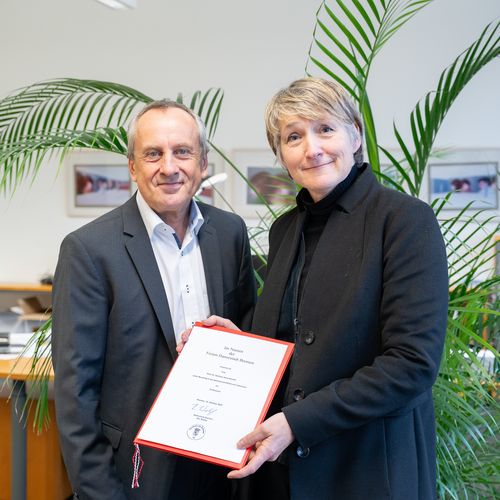 Rektor Prof. Dr. Konrad Wolf und Prof. Dr. Stefanie Bremer. schauen in die Kamera. Frau Bremer h&auml;lt ihrer Ernennungsurkunde 