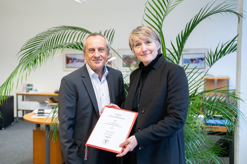 Rektor Prof. Dr. Konrad Wolf und Prof. Dr. Stefanie Bremer. schauen in die Kamera. Frau Bremer h&auml;lt ihrer Ernennungsurkunde 