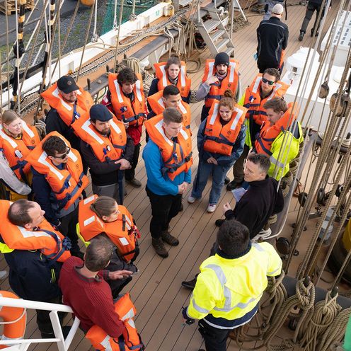 Studierende der HSB und Crew in Schwimmwesten an Deck auf dem Gro&szlig;segler Alex-2