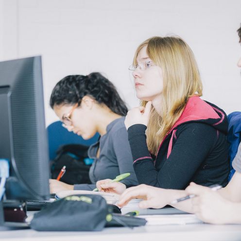 Drei Studierende arbeiten an Computern. 