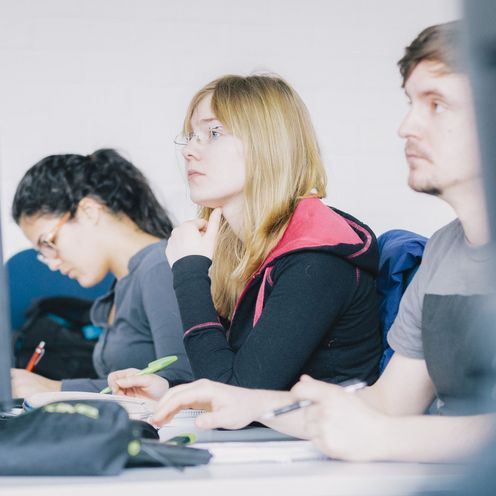 Drei Studierende arbeiten an Computern. 