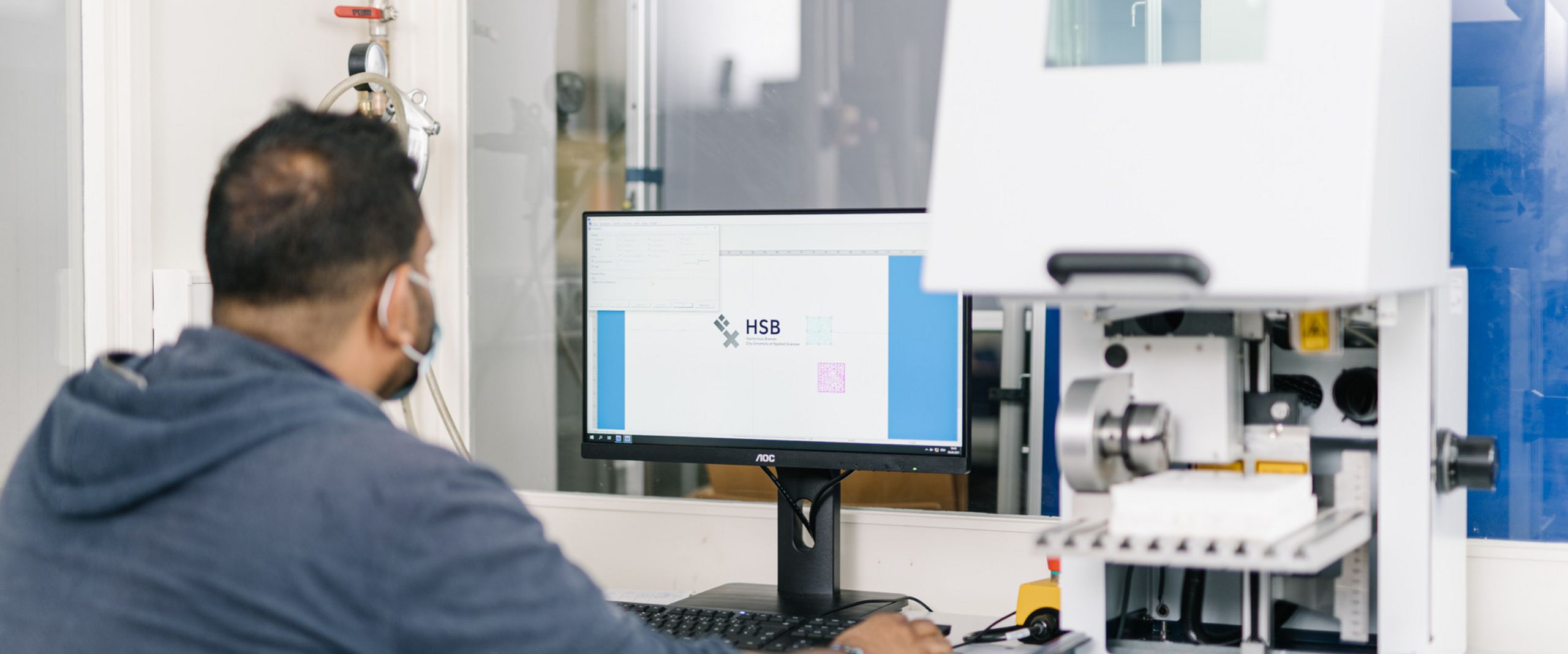 Ein Studierender bei der Arbeit an einer Lasergravurmaschine 