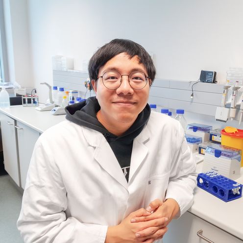 Mann sitz im wei&szlig;en Kittel im Labor und l&auml;chelt in die Kamera