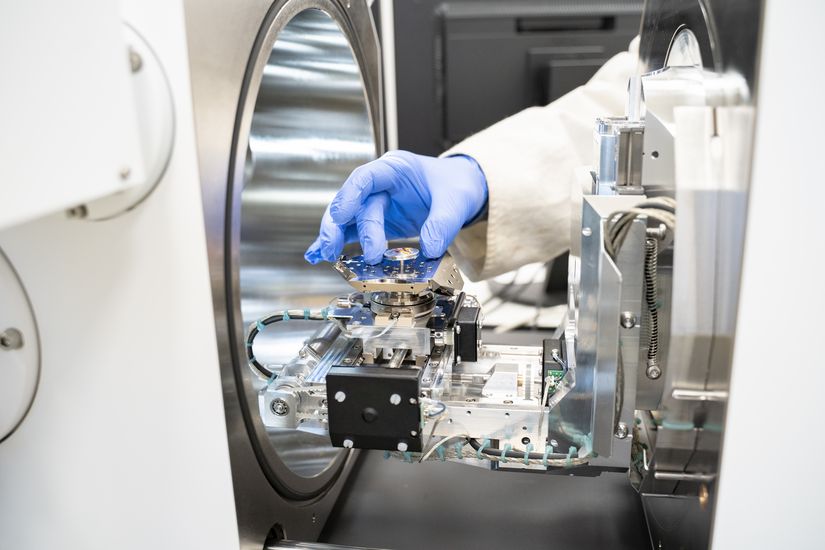 Bld zeigt Hand mit blauem Handschuh, die eine Probe in einem kleinen Beh&auml;lter zeigt.