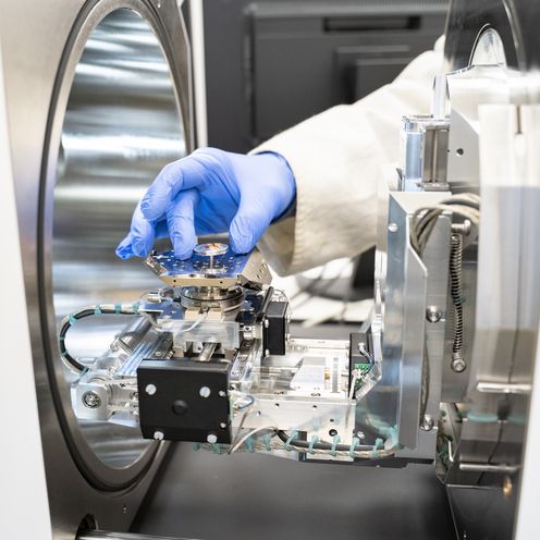 Bld zeigt Hand mit blauem Handschuh, die eine Probe in einem kleinen Beh&auml;lter zeigt.