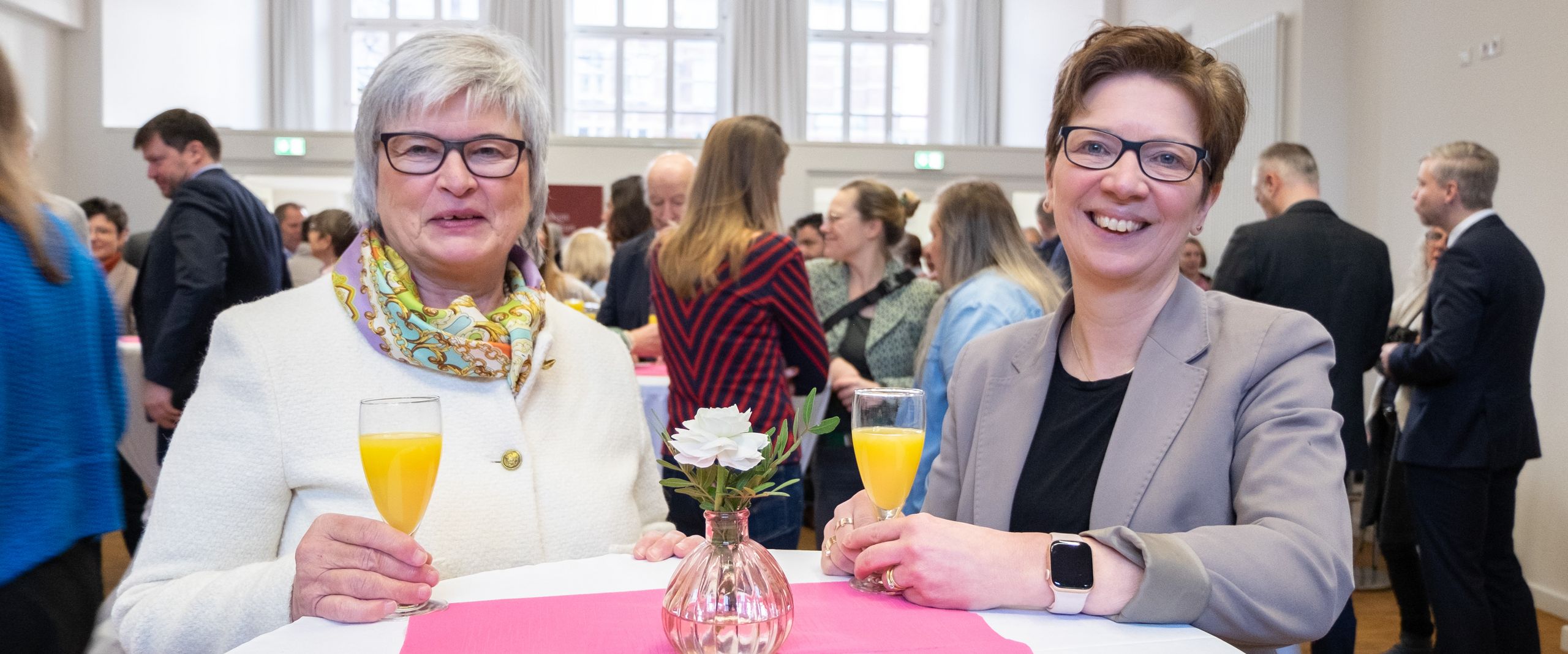 Zwei Frauen schauen l&auml;chelnd in die Kamera.