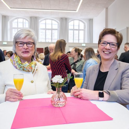 Zwei Frauen schauen l&auml;chelnd in die Kamera.