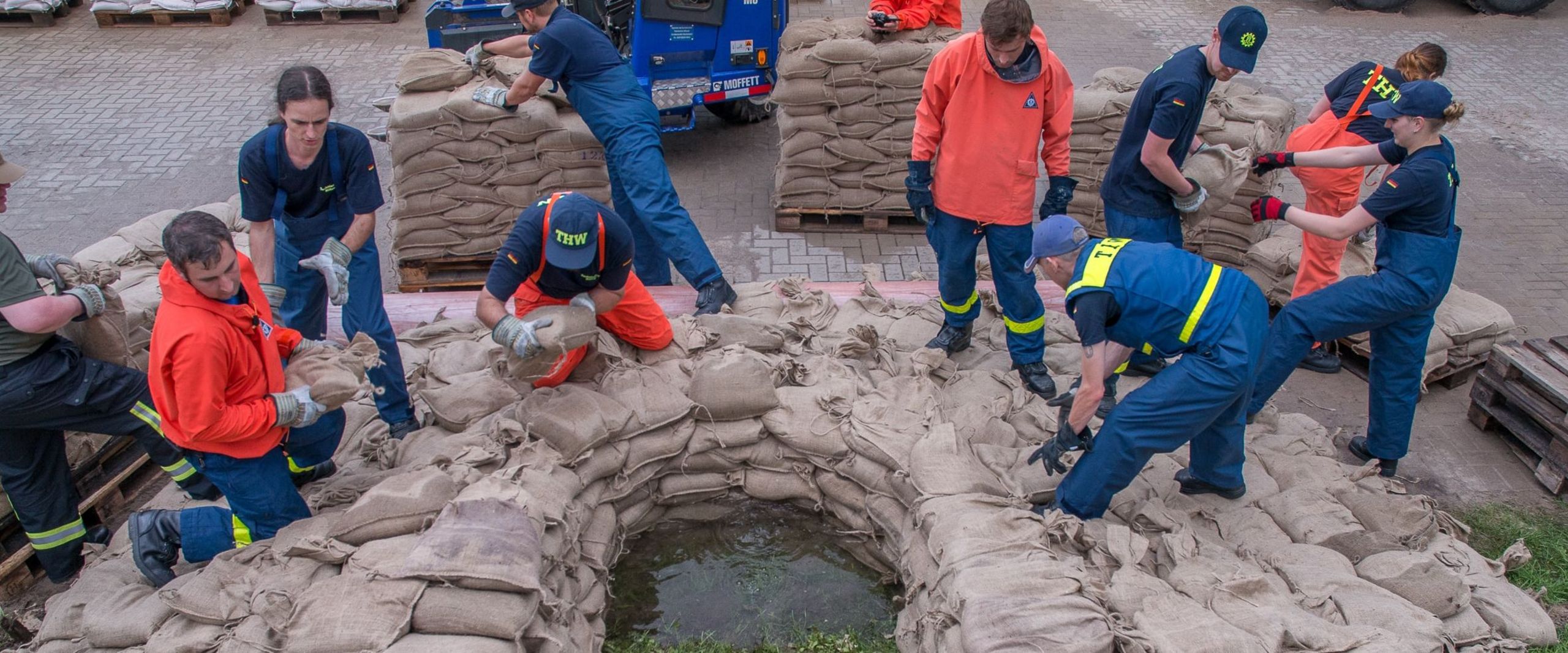 Mitglieder des Technischen Hilfswerk errichten einen Damm aus Sandsäcken.