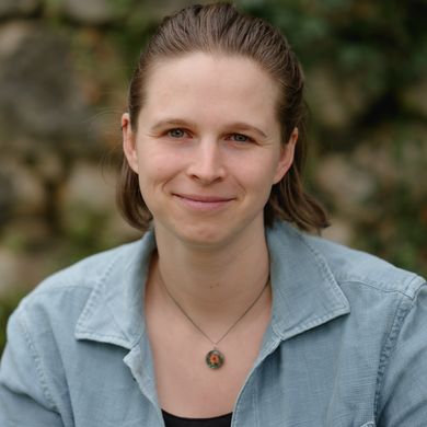 Auf dem Bild ist Rahel Louise Schmied-Kowarzik zusehen. Sie hat braunes kinnlanges Haar und trägt ein schwarzes Oberteil unter einer hellblauen Jeansjacke.