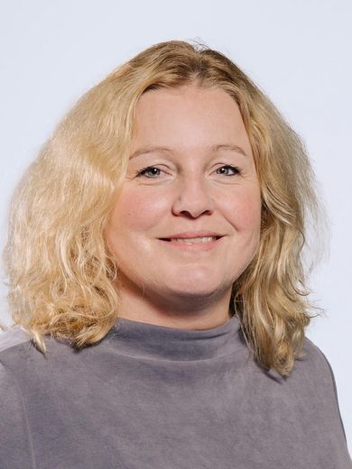 Auf dem Foto ist Mechtild Bode-Wübbeler zusehen. Sie hat blonde lockige Haare und trägt einen blau-grauen Pullover.