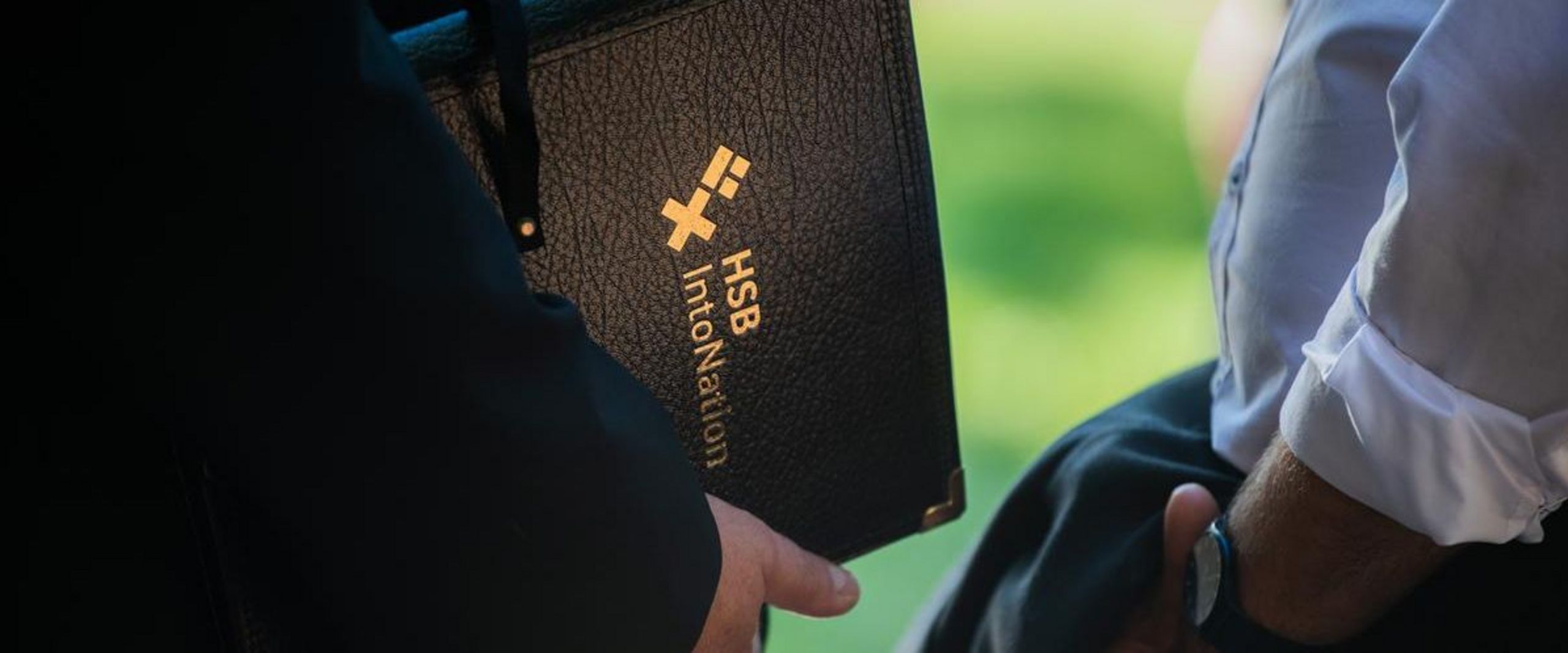 Zwei Dirigenten halten eine Mappe mit der Aufschrift HSB IntoNation und eine Jacke in ihren Händen.