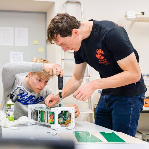 VIBES Belgien_Studierende bei den Vorbereitungen Zwei Studierende schrauben an einem technischen Gerät auf einem Tisch.