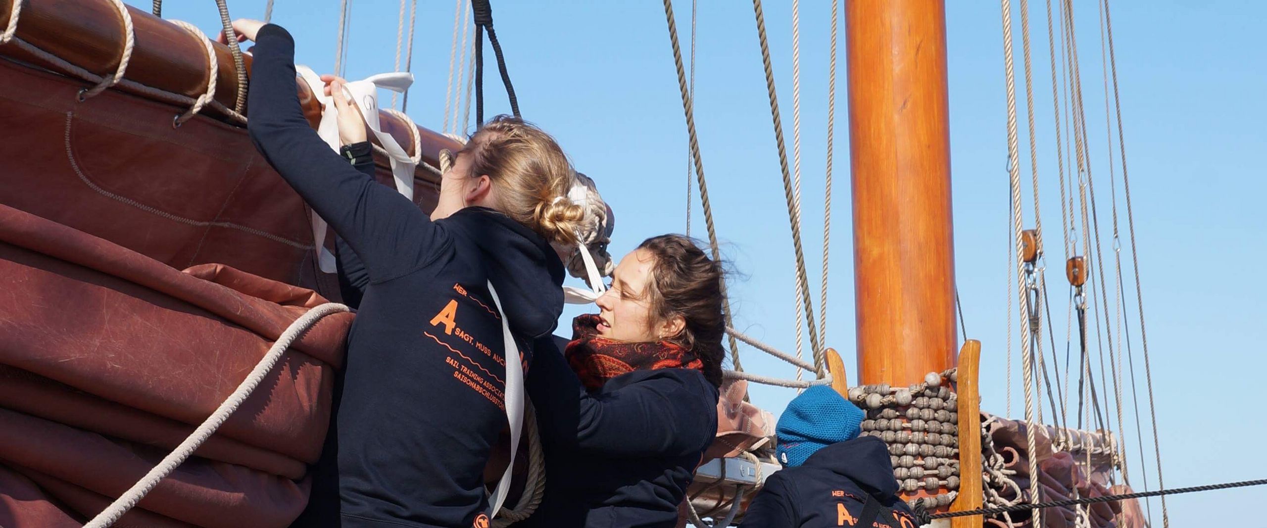 Menschen auf einem Hozboot. Sie holen die Segel ein.