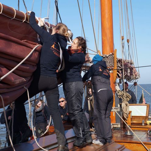 Menschen auf einem Hozboot. Sie holen die Segel ein.