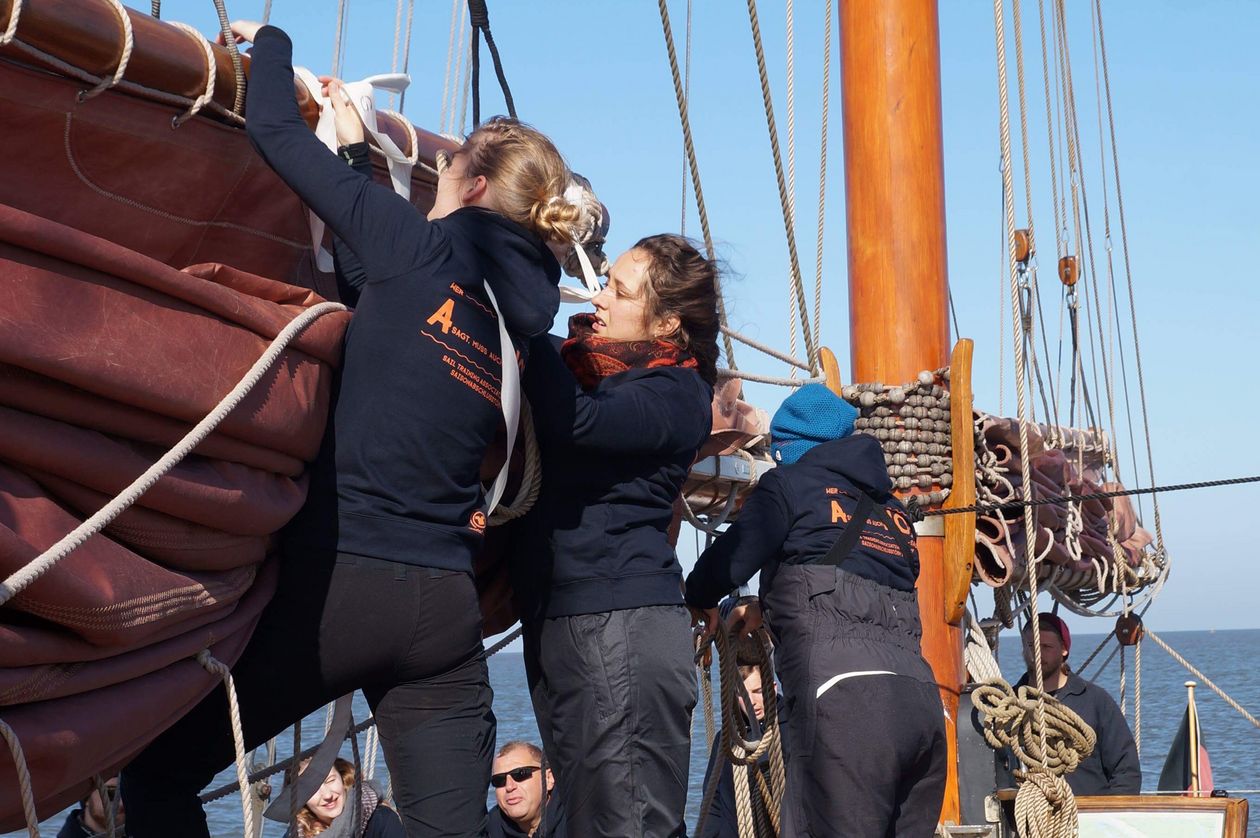 Menschen auf einem Hozboot. Sie holen die Segel ein.