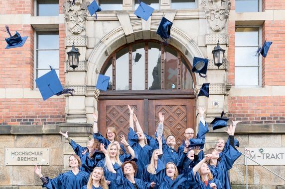 Absolventinnen und Absolventen werfen Hüte in die Höhe