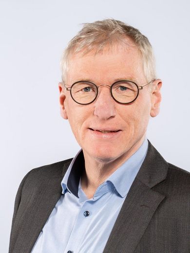 Auf dem Foto ist Hanno Feidicker zusehen. Er hat kurze graue Haare. Er tr&auml;gt eine runde braune Brille, ein blaues Hemd und braunes Jacket.