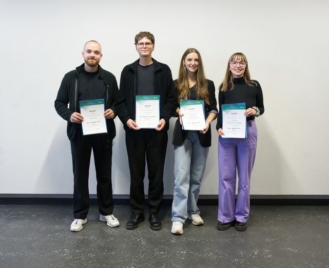 Gruppenbild mit zwei jungen Männern und zwei jungen Frauen, die eine Urkunde halten