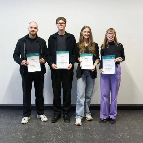 Gruppenbild mit zwei jungen M&auml;nnern und zwei jungen Frauen, die eine Urkunde halten