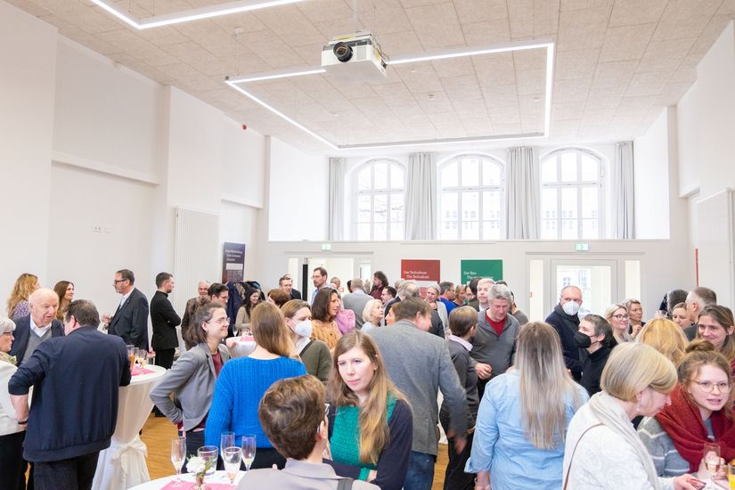 Menschen stehen an Stehtischen und unterhalten sich