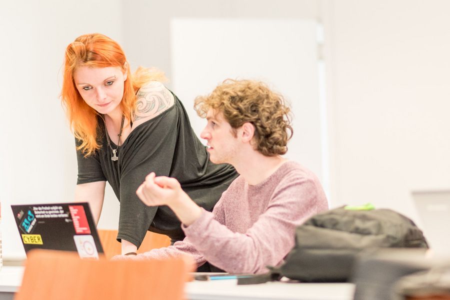 Zwei Studierende betrachten einen Laptop. 