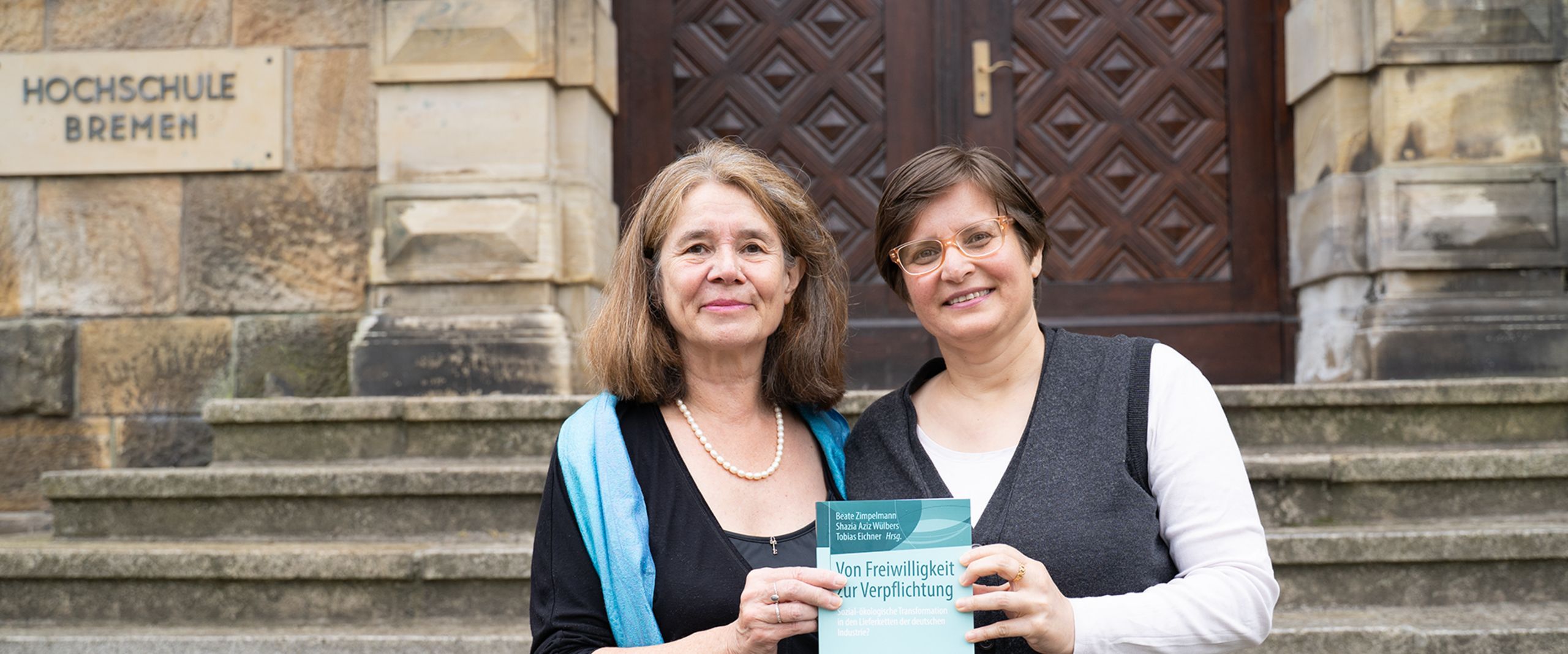 Die Professorinnen Zimpelmann und W&uuml;lbers pr&auml;sentieren ihr Buch "Von Freiwilligkeit zur Verpflichtung" vor dem M-Geb&auml;ude der HSB