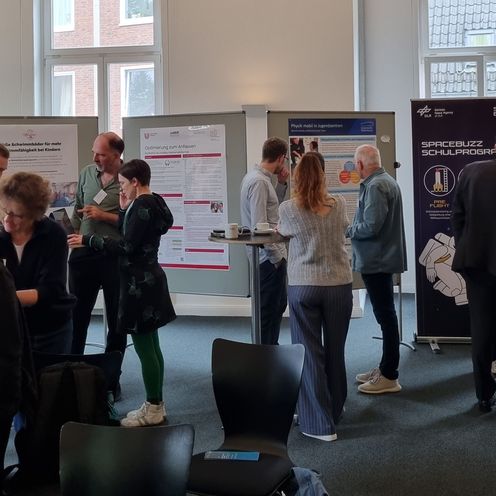 Ausstellungsteilnehmer:innen schauen sich die Ausstellung an