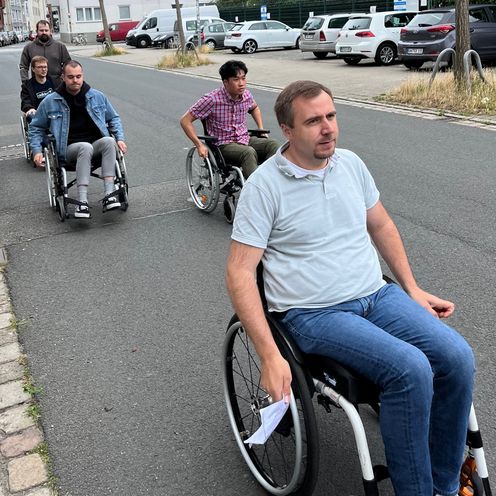 mehrere HSB Studierende fahren in Rollst&uuml;hlen eine Stra&szlig;e entlang